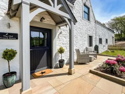 a stone house with a door and a patio at The Old Coach House At Balcary in Auchencairn