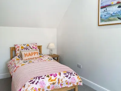 a bedroom with a bed with a happy pillow on it at The Old Coach House At Balcary in Auchencairn