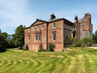 an old brick building on a grass field at Amisfield Tower in Dumfries