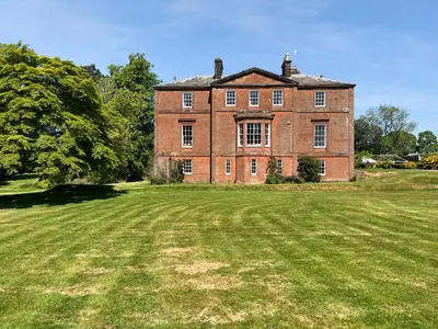 an old brick house with a large grass field at Amisfield Tower in Dumfries