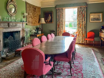 a dining room with a wooden table and red chairs at Amisfield Tower in Dumfries