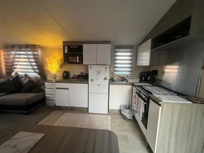 a kitchen with a white refrigerator and a couch at the heaths caravan hire Craig Tara in Minishant