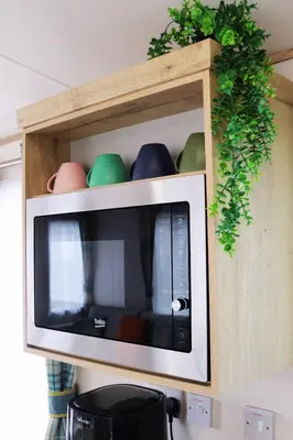 a microwave in a wooden cabinet with green plants at Relax, Enjoy fast Starlink Wi-Fi in Carlisle