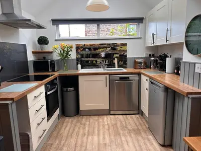 a kitchen with white cabinets and a sink at Charming cosy cottage near the Lake District in Penrith