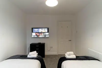 a bedroom with two beds and a tv on the wall at Lovely 2 Bed Harbourside Apartment with Sea Views in Whitehaven