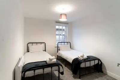 two twin beds in a room with a window at Lovely 2 Bed Harbourside Apartment with Sea Views in Whitehaven
