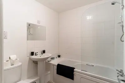 a white bathroom with a sink and a bath tub at Lovely 2 Bed Harbourside Apartment with Sea Views in Whitehaven