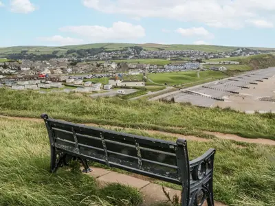 a black bench sitting on a hill overlooking a town at Puffin in St Bees