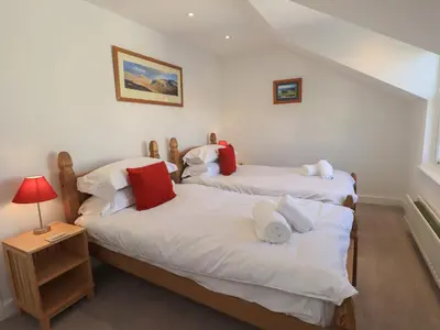 two twin beds in a room with a lamp on a table at Swirl Howe in Keswick