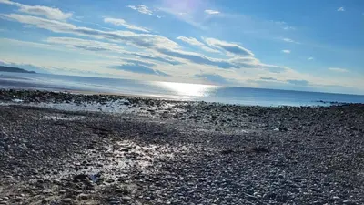 a rocky beach with the sun shining on the water at Bega House Apartment in Whitehaven