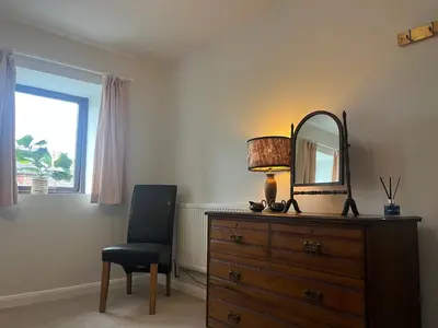a bedroom with a dresser with a mirror and a chair at Stay Still Indian Court in Dalston