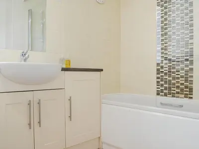 a white bathroom with a sink and a bath tub at Brigham Farm Apartments in Keswick