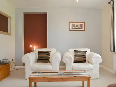 a living room with two white chairs and a coffee table at Brigham Farm Apartments in Keswick