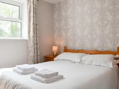 a bedroom with a bed with white towels on it at Brigham Farm Apartments in Keswick