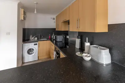 a kitchen with a washing machine and a black counter top at Bright 1 Bed Harbour-side Apartment with Sea Views in Whitehaven