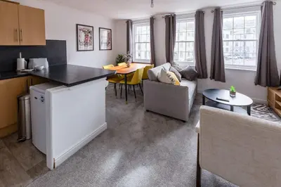 a kitchen and living room with a table and a couch at Bright 1 Bed Harbour-side Apartment with Sea Views in Whitehaven