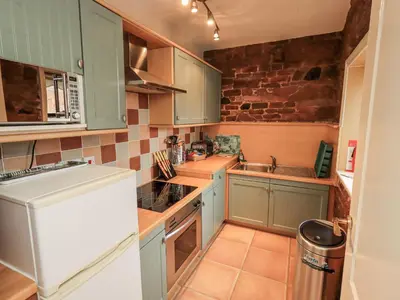a kitchen with blue cabinets and a white refrigerator at The Coach House in Wigton