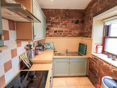 a small kitchen with a sink and a brick wall at The Coach House in Wigton