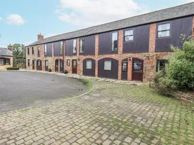 a brick building with a parking lot in front of it at Millers Cottage in Wigton