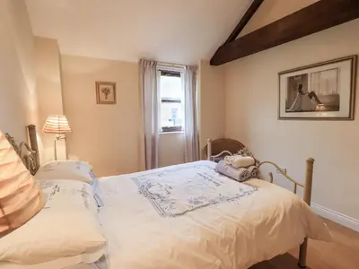 a bedroom with a bed and a window at Millers Cottage in Wigton
