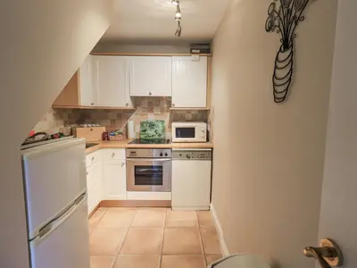 a small kitchen with white cabinets and appliances at Millers Cottage in Wigton