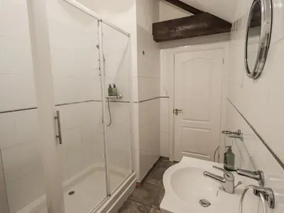 a white bathroom with a shower and a sink at Millers Cottage in Wigton