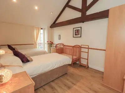 a bedroom with two beds and a wooden floor at The Hayloft in Wigton