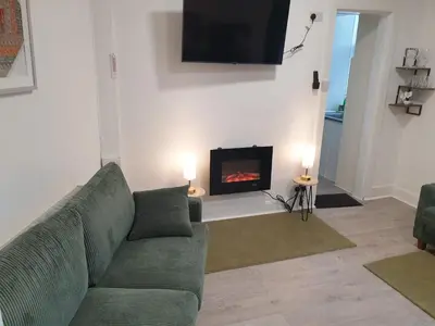 a living room with a couch and a fireplace at Modern Two-Bedroom Apartment Near River with Free Parking & WiFi in Dumfries