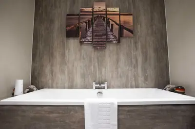 a bath tub in a bathroom with a painting of a pier at Fellside Hideaway in Keswick