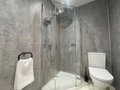 a bathroom with a toilet and a glass shower at Fellside Hideaway in Keswick
