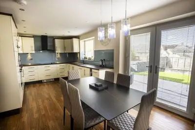 a kitchen with a black table and chairs and a kitchen with a window at Fellside Hideaway in Keswick