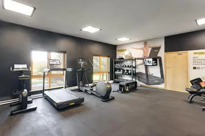 a gym with cardio equipment and a woman on the wall at The Hide - Ridgestone in Penrith