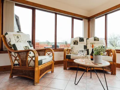 a room with chairs and a table and windows at Middle Byre in Girthon