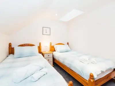 two beds in a room with white sheets at The Barn in Girthon