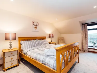 a bedroom with a wooden bed and a window at The Barn in Girthon
