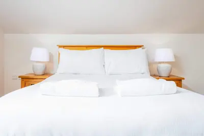a white bed with white pillows and two lamps at The Portland Penthouse - Donnini Apartments in Troon
