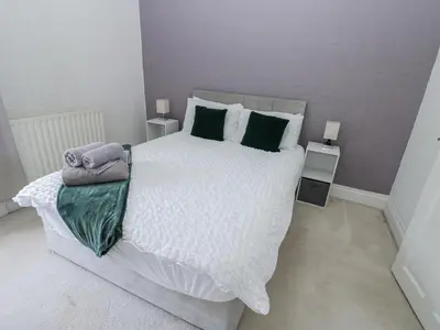 a bedroom with a large white bed with green pillows at Cumberland House in Workington