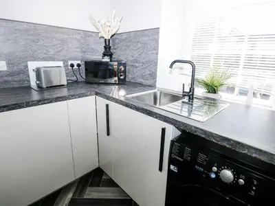 a kitchen with white cabinets and a sink at Lowther House in Whitehaven