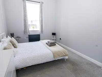 a white bedroom with a bed and a window at Lowther House in Whitehaven