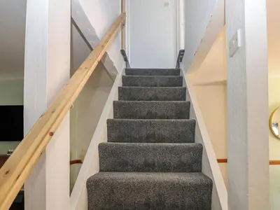 a staircase in a house with grey carpeting and wooden railings at Bolton Terrace in Workington