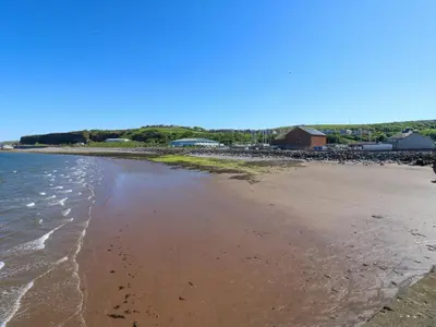a sandy beach with a group of buildings in the background at Lowther Suite in Whitehaven