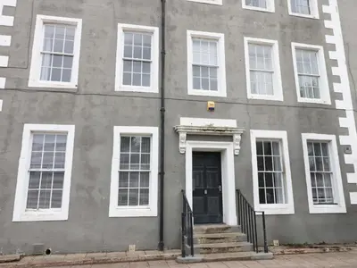 a gray building with white windows and a door at Lowther Suite in Whitehaven