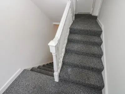a staircase in a house with a white rail and grey carpet at Georgian Town House in Whitehaven