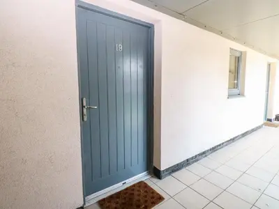 a blue door in a hallway with a tile floor at Pears Suite in Whitehaven