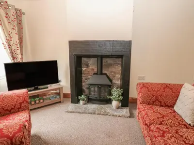 a living room with a fireplace and a tv at Kirkgate Cottage in Cockermouth