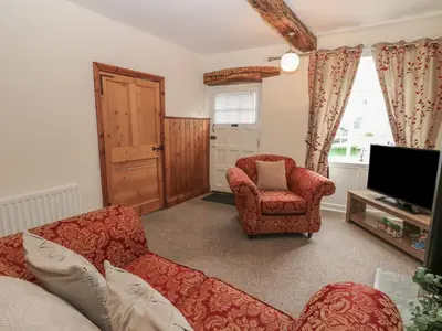 a living room with a couch and a chair and a television at Kirkgate Cottage in Cockermouth