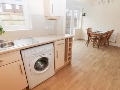 a kitchen with a washing machine and a table at Lingla House in Frizington