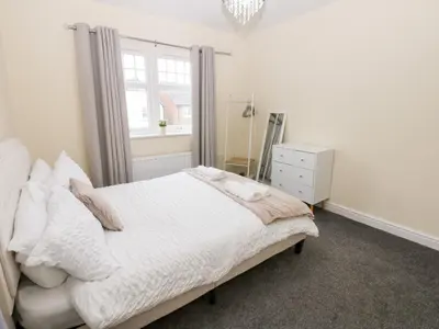 a white bedroom with a bed and a window at Lingla House in Frizington