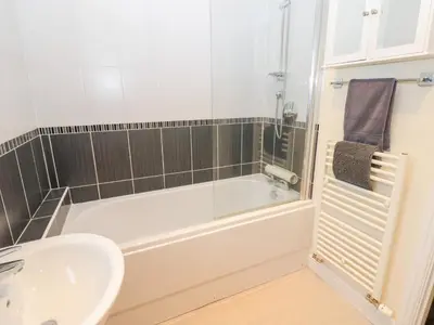 a bathroom with a white tub and a sink at Lingla House in Frizington