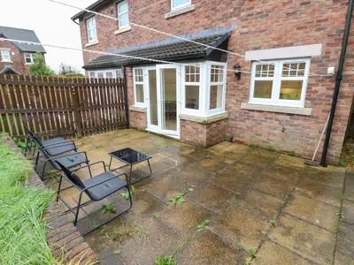a patio with chairs and a table in front of a house at Lingla House in Frizington